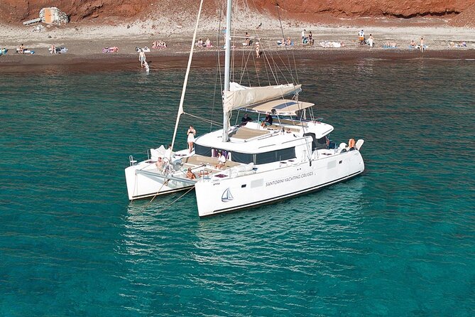 Santorini Sunset Sailing Cruise: Dinner, BBQ, Open Bar, Transfers - Red Beach: a striking first stop